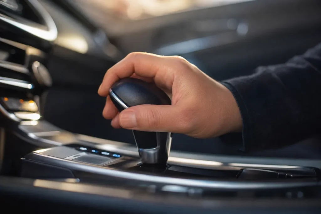 Hand op de keuzehendel van een automatische versnellingsbak in een moderne auto