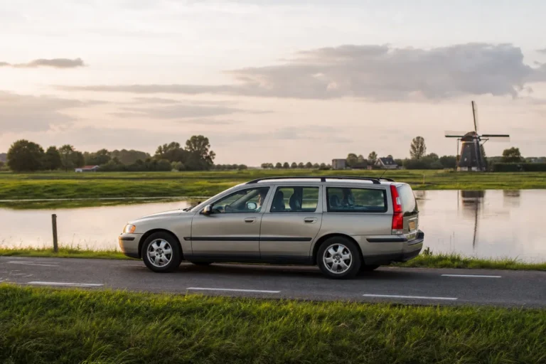 Oudere auto met automaat rijdt over een landweg langs een kanaal