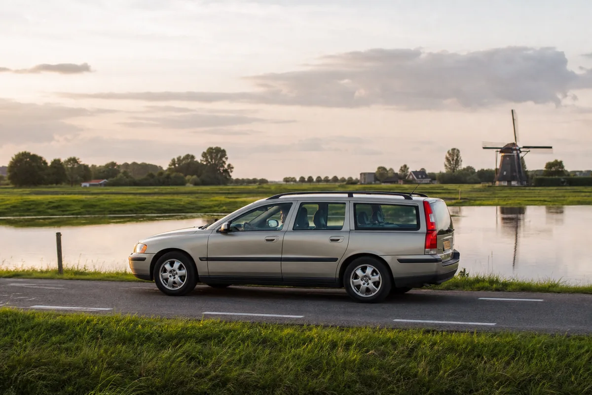 Oudere auto met automaat rijdt over een landweg langs een kanaal